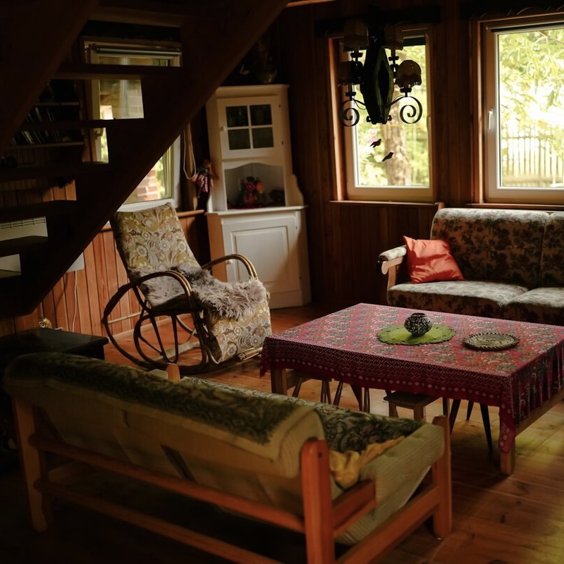 Drewniane wnętrze domku Villa Isabel z trzema kanapami, stołem przykrytym obrusem i bujanum krzesłem