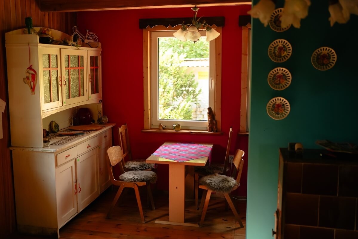 Jadalnia z drewnianymi krzesłami i dużą, białą komodą