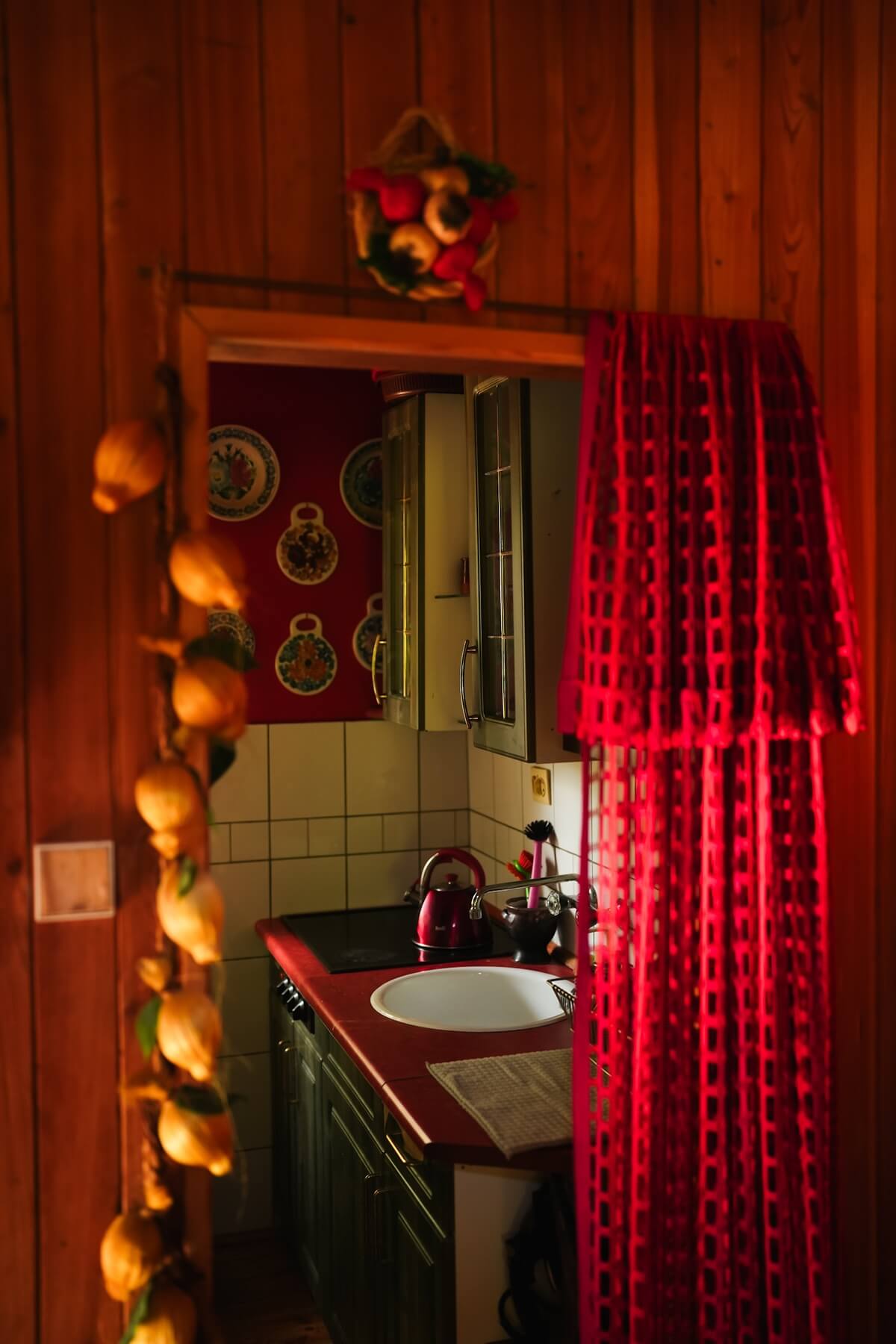 Wejście do kuchni z czerwoną zasłoną i ozdobą z cytryn wiszących na sznurku